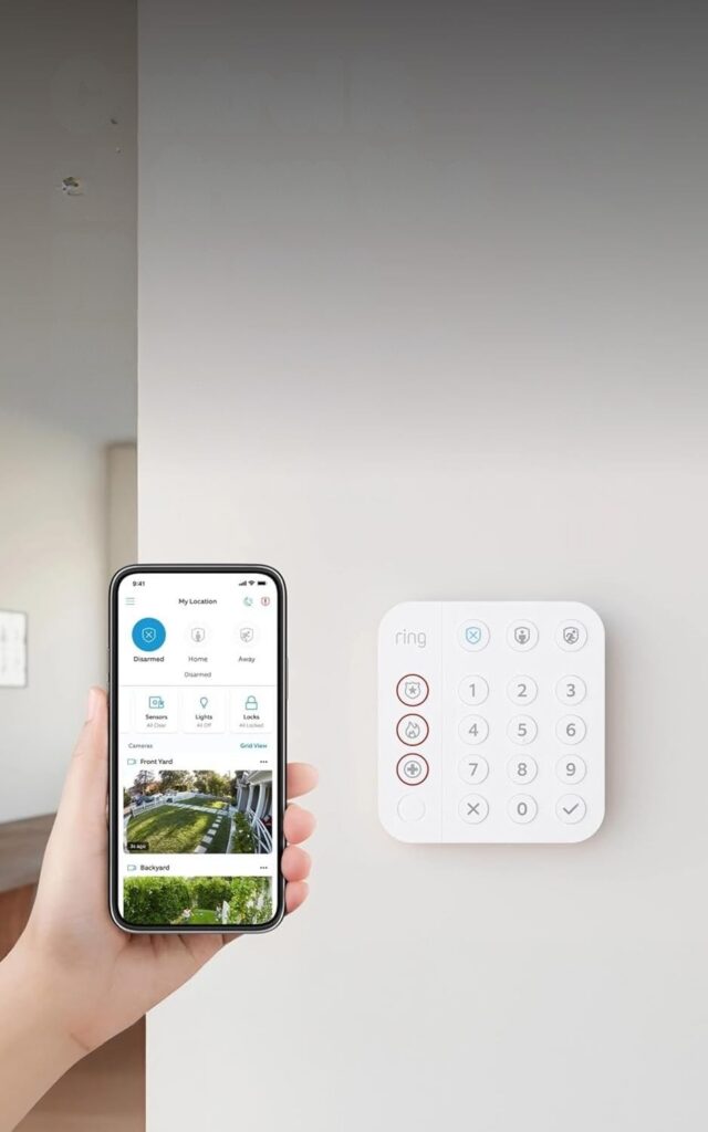 Ring Alarm keypad on a wall next to the Ring app on a phone