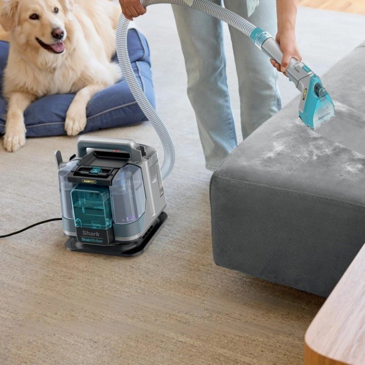 Shark StainStriker HairPro portable cleaner lifting a stain from a gray couch